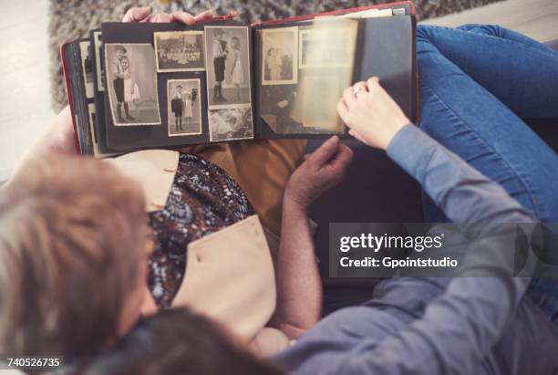 overhead view of young woman on sofa with grandmother looking at photo album - looking to the past stock pictures, royalty-free photos & images