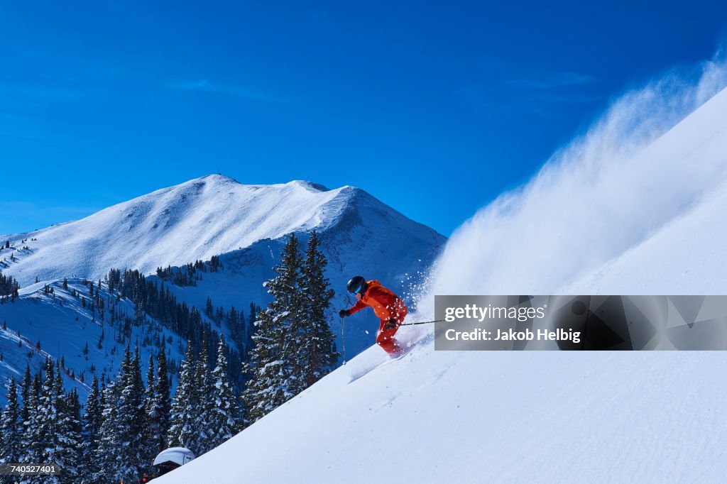 Man skiing down steep snow covered mountainside, Aspen, Colorado, USA