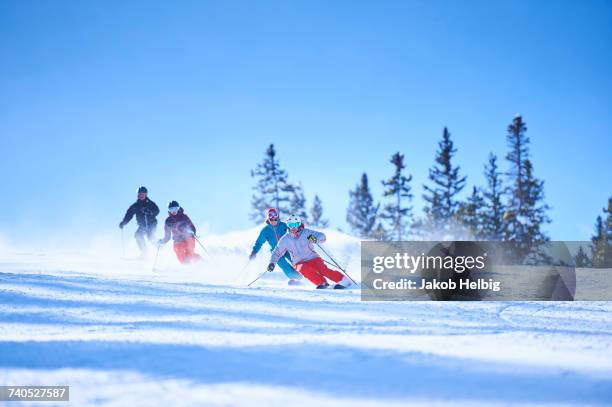 male and female skiers skiing down snow covered ski slope, aspen, colorado, usa - aspen colorado winter stock pictures, royalty-free photos & images