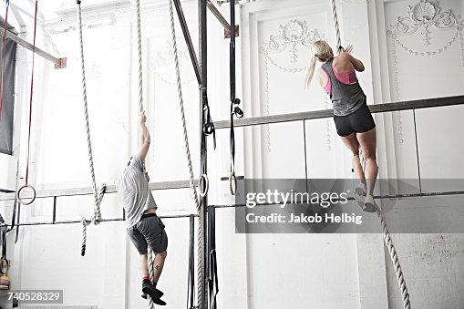 Couple rope climbing in cross training gym Couple rope climbing in cross training gym