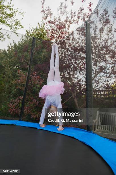 girl on trampoline wearing tutu doing handstand - girl in dress doing handstand stockfoto's en -beelden