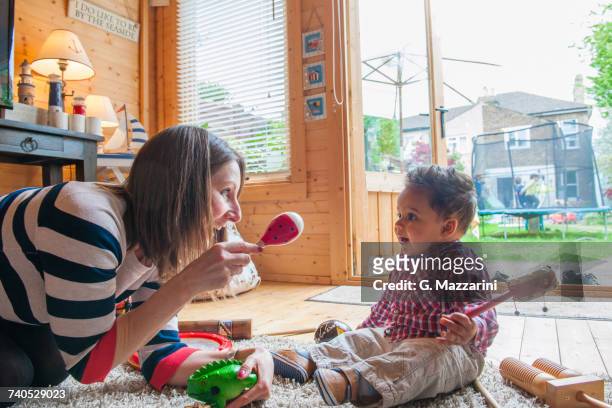 childminder shaking maraca at baby boy - nanny stock pictures, royalty-free photos & images