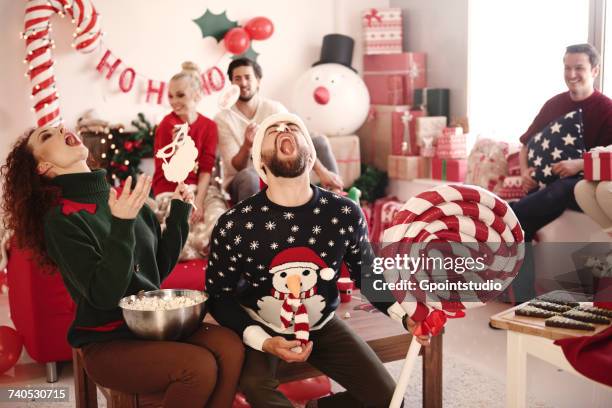 young woman and man catching popcorn in open mouths at christmas party - daily life during christmas season in poland foto e immagini stock