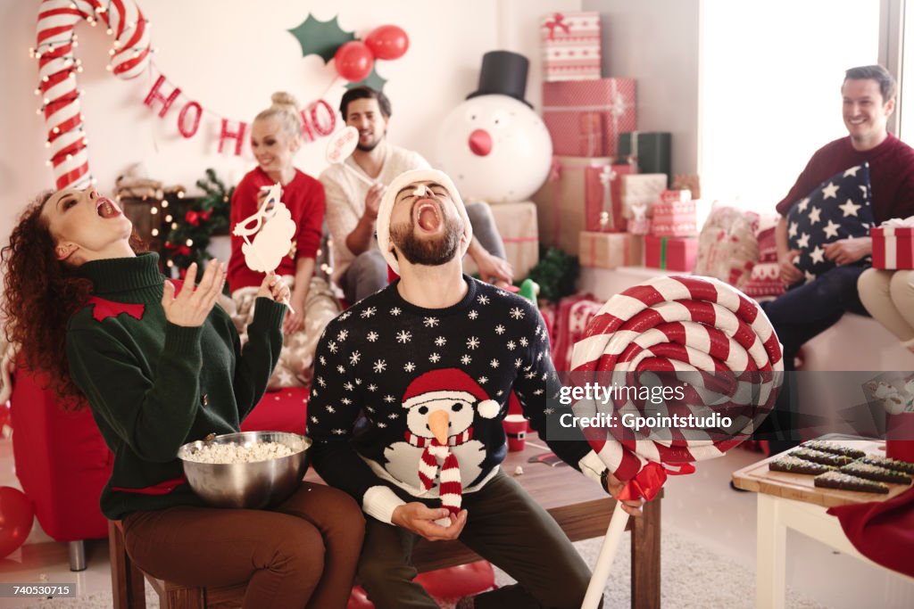 Young woman and man catching popcorn in open mouths at christmas party