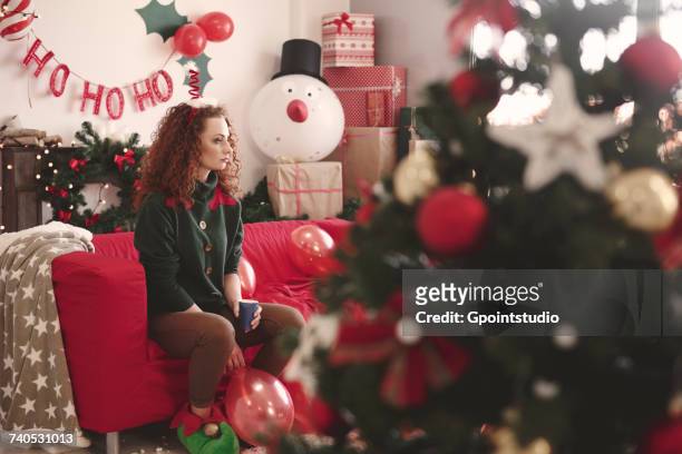sad young woman sitting alone on sofa at christmas - solitude stock pictures, royalty-free photos & images
