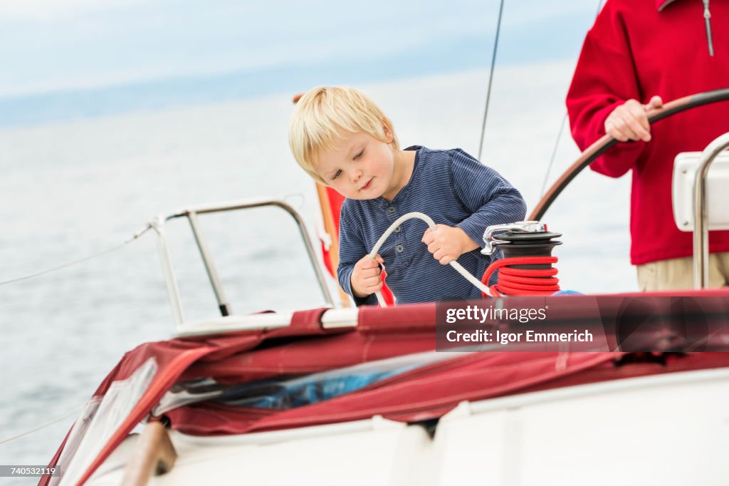 Young boy on sailing boat with great grandfather, mid section, Geneva, Switzerland, Europe