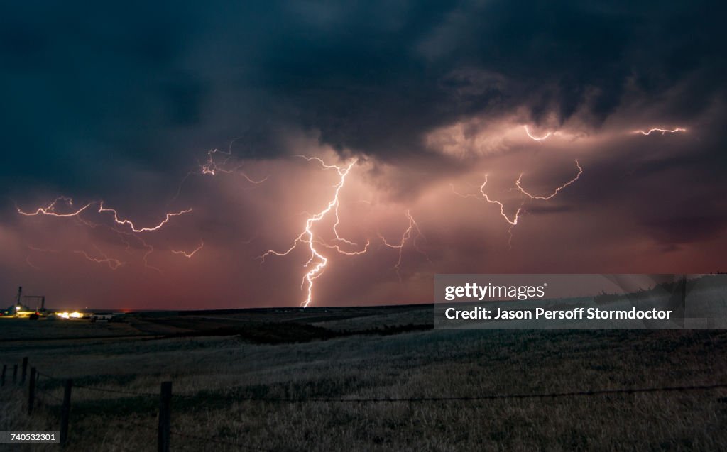Forked lightning in orange sky over rural area, Grant, Nebraska, United States, North America