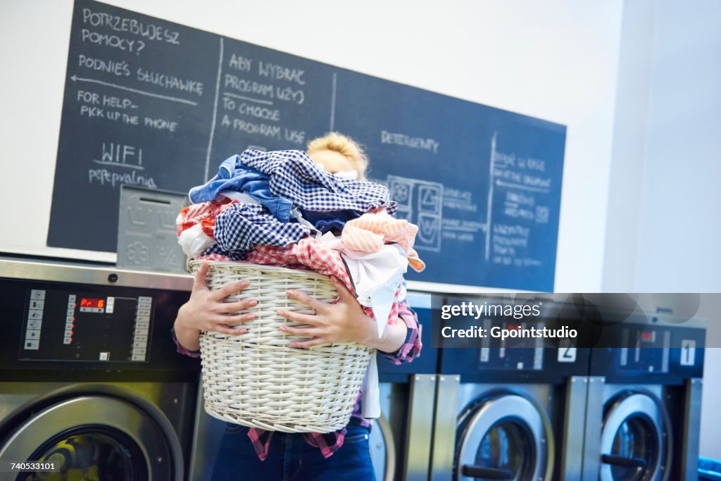 Woman in laundrette carrying full laundry basket