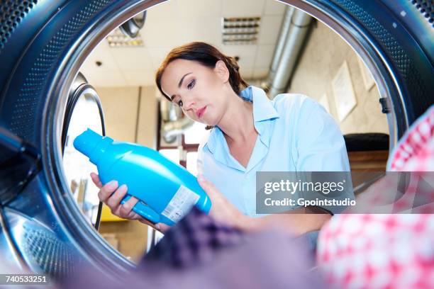 woman looking at fabric conditioner for washing machine laundry at laundrette - wasmiddel stockfoto's en -beelden