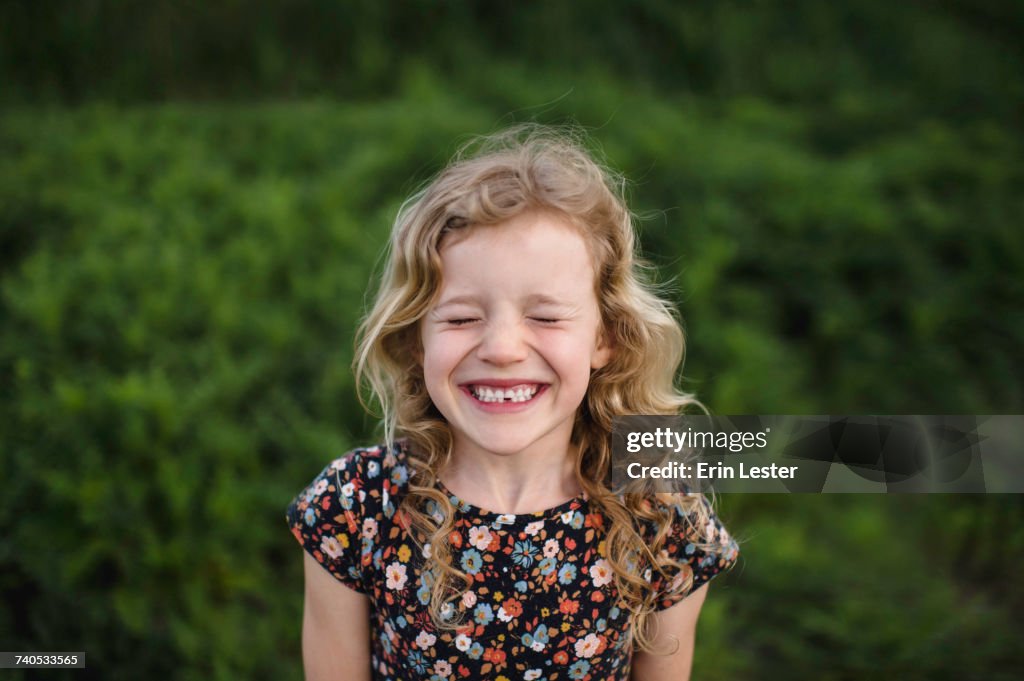 Portrait of girl with wavy blond hair and missing tooth in field
