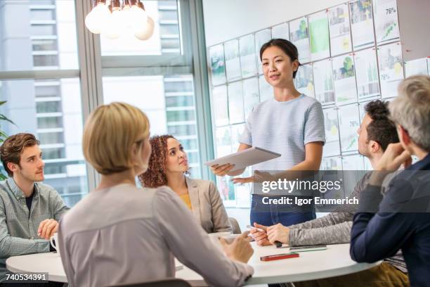 female digital designer explaining ideas to team at conference table - conference table top stock pictures, royalty-free photos & images