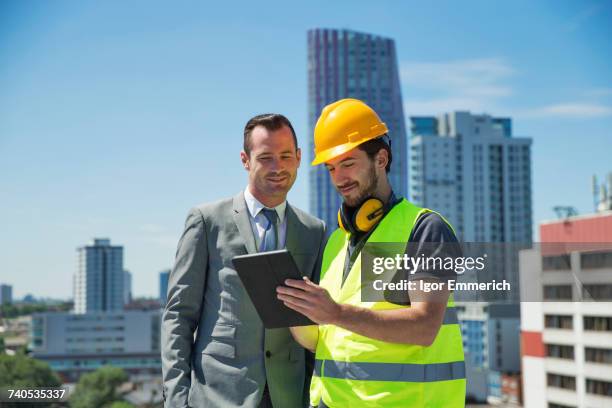 businessman and construction worker, outdoors, looking at digital tablet - real estate developer stock pictures, royalty-free photos & images