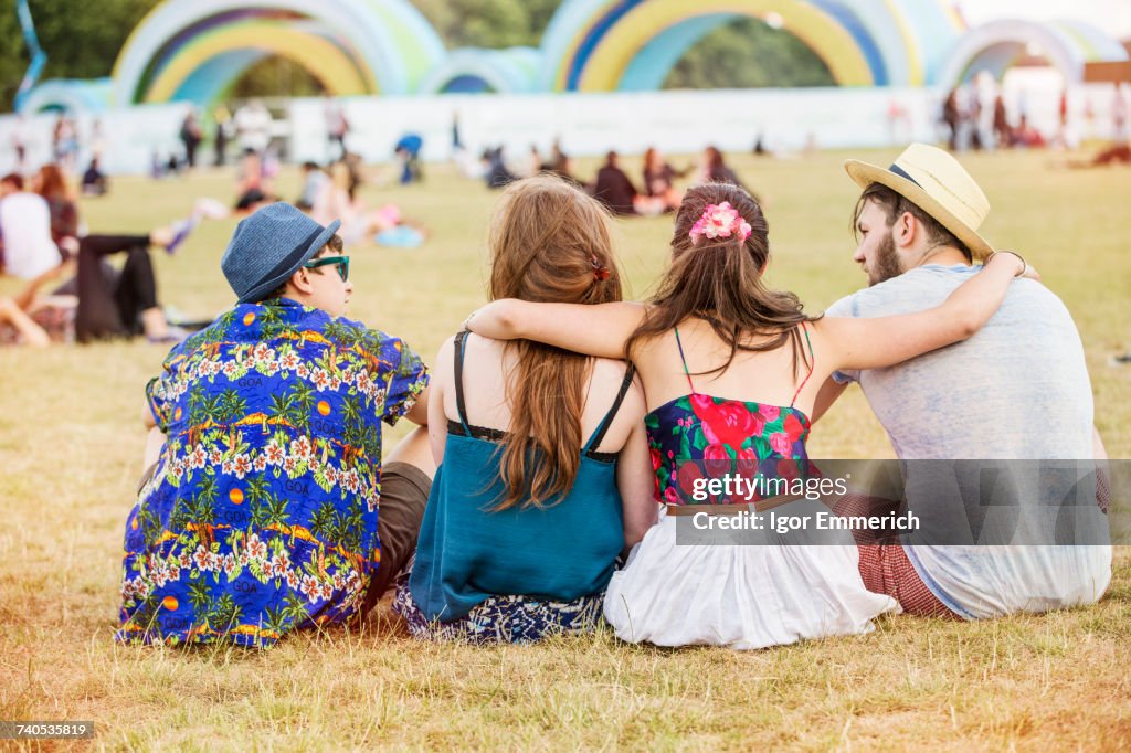 Rear view of friends sitting on grass at festival