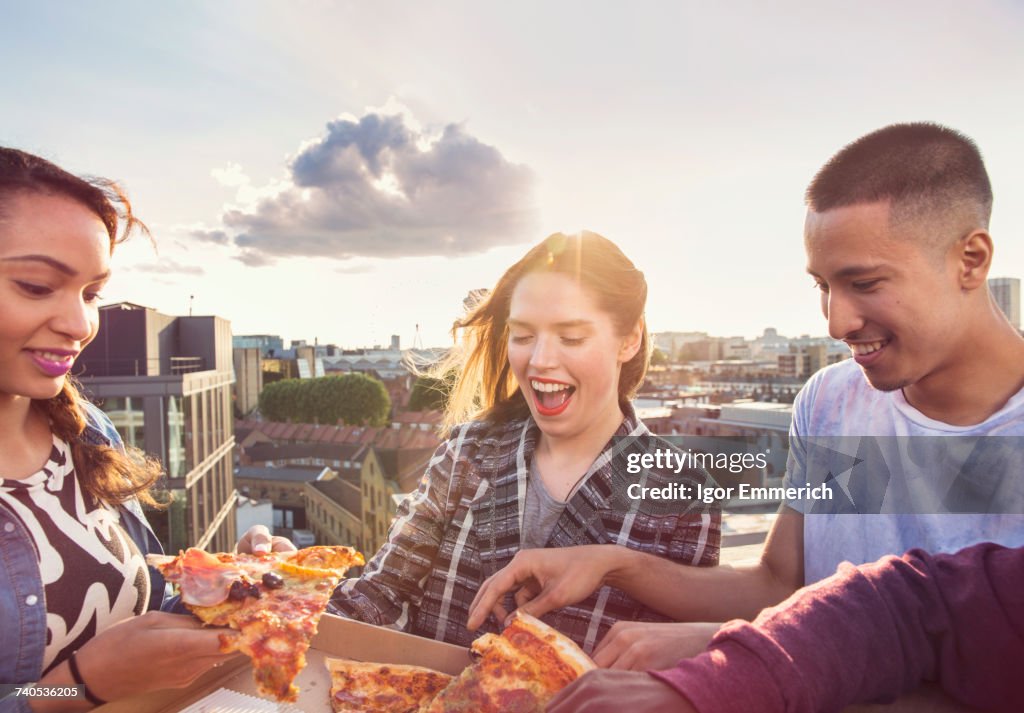 Young adult friends sharing pizza at roof party in London, UK