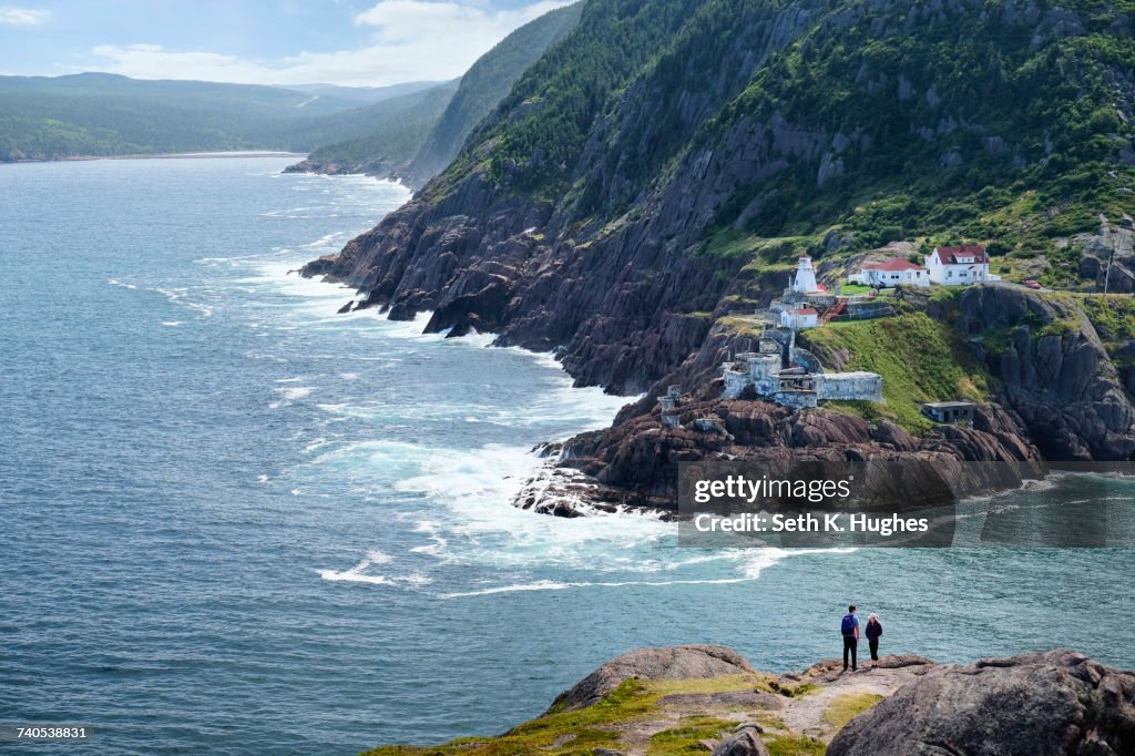 Couple looking out from coastal cliff, St Johns, Newfoundland, Canada