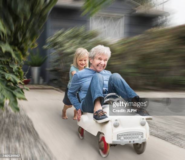 grandson pushing grandmother on his toy car - memorial garden stock pictures, royalty-free photos & images