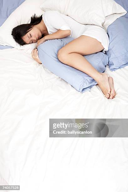 young woman sleeping on bed with pillow between knees - human knee stock pictures, royalty-free photos & images
