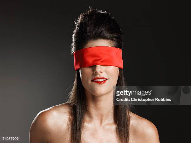 young woman wearing red blindfold, biting lip - blinddoek stockfoto's en -beelden