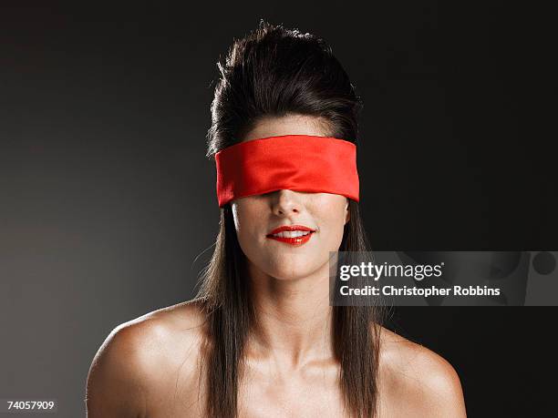 young woman wearing red blindfold, biting lip - blind fold stock pictures, royalty-free photos & images