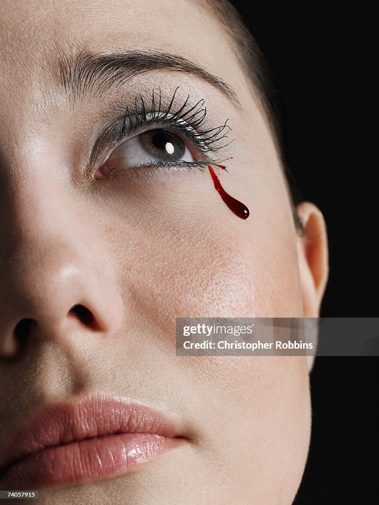 Young woman crying tear of blood, close-up of face