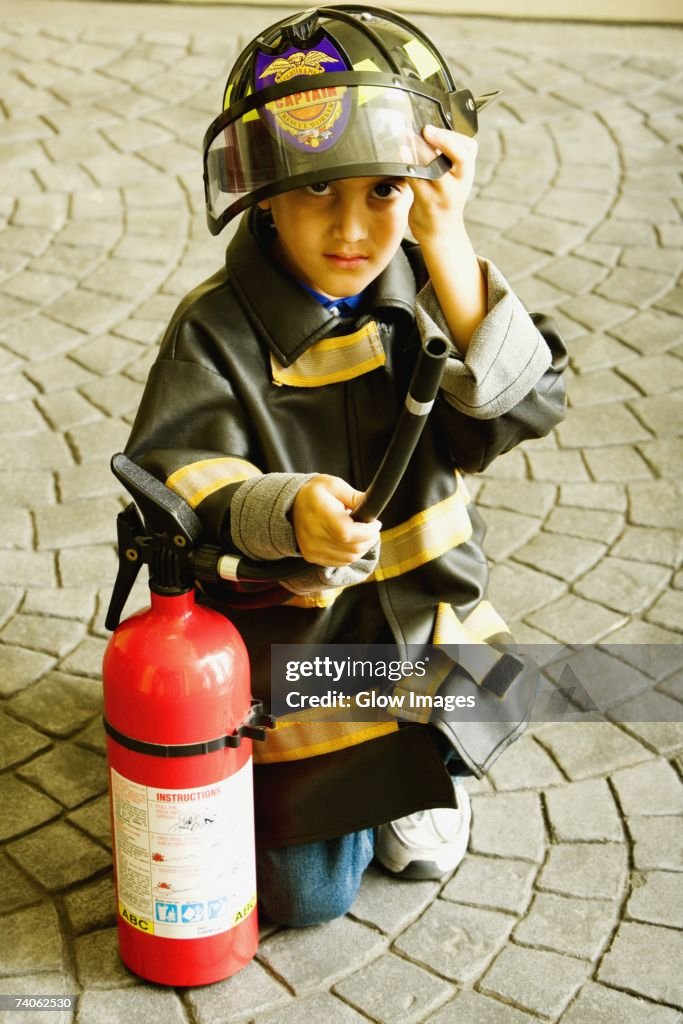 Portrait of a boy dressed as a firefighter and holding a fire extinguisher