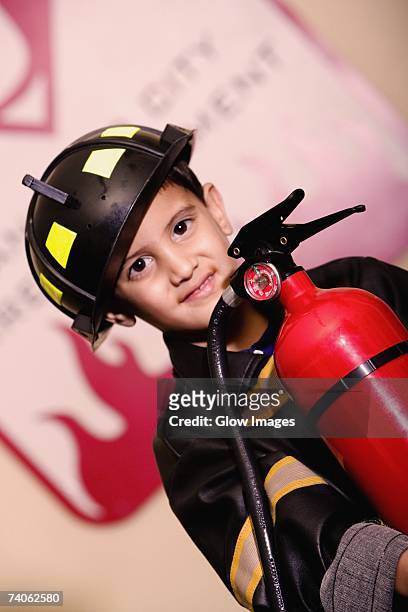 portrait of a boy dressed as a firefighter and holding a fire extinguisher - boy fireman costume stock pictures, royalty-free photos & images