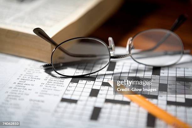 close-up of a pencil and a pair of eyeglasses on a crossword puzzle - kruiswoordpuzzel stockfoto's en -beelden