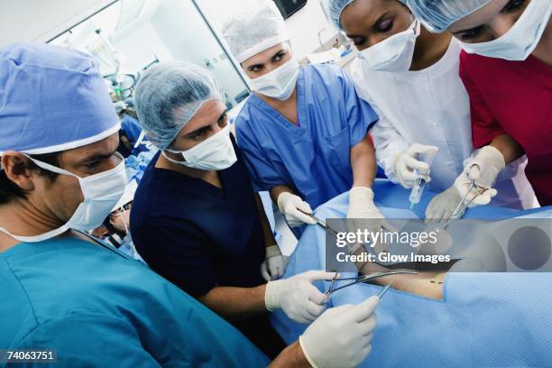 three female surgeons and two male surgeons operating a patient - man lying on operating table stock pictures, royalty-free photos & images
