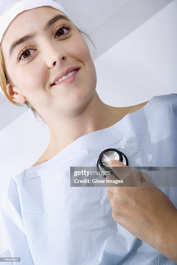 Close-up of a doctor's hand holding a stethoscope and examining a female patient