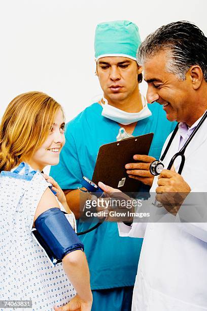 side profile of a male doctor measuring blood pressure of a young woman - surgical mask profile stock pictures, royalty-free photos & images