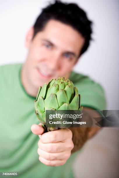 close-up of a mid adult man holding an artichoke - artichoke stock pictures, royalty-free photos & images