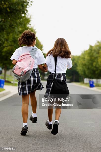rear view of two schoolgirls walking with holding hands - nur mädchen stock-fotos und bilder