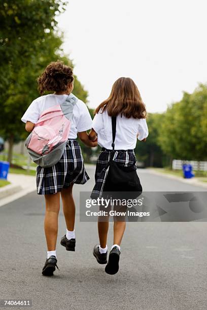 rear view of two schoolgirls walking with holding hands - solo bambine femmine foto e immagini stock