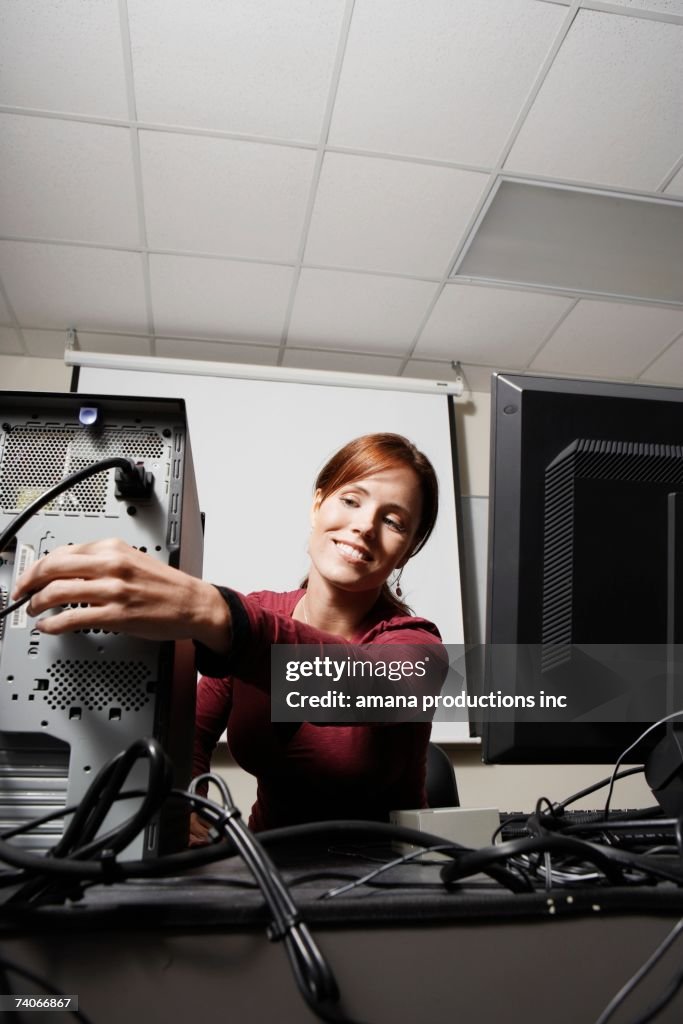 Female college student adjusting computer cable