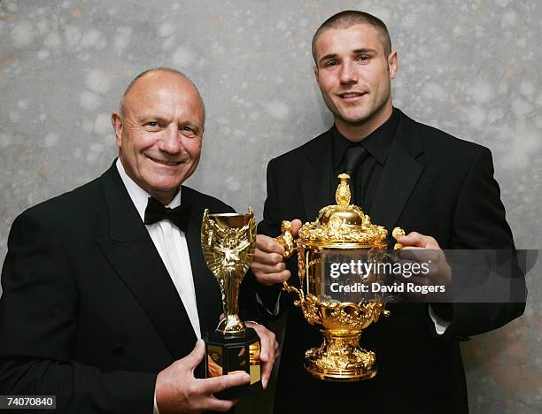 George Cohen poses with a replica of the Jules Rimet Trophy and his nephew Ben Cohen, holding the Webb Ellis Trophy at a fundraising dinner at...