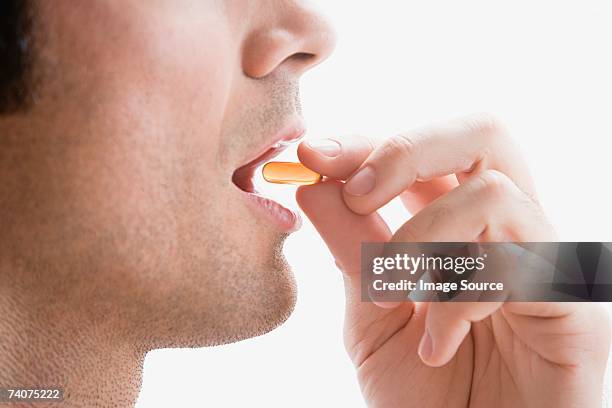 man taking a vitamin pill - finger tablet stock pictures, royalty-free photos & images