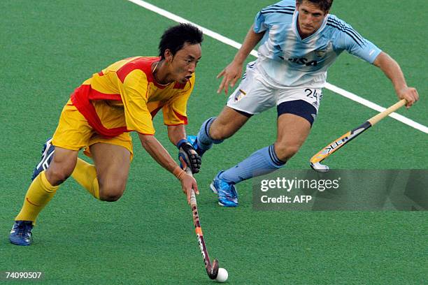 China's Feng Hui Lu controls the ball as Argentina's Gomas Argento gives chase during the third day of the 16th Sultan Azlan Shah hockey tournament...