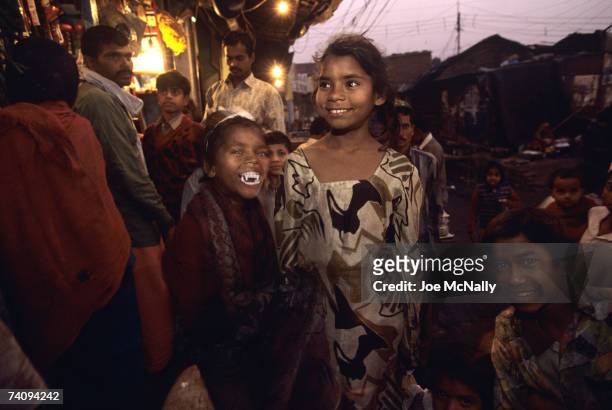 Young girl shows off her fake fangs in the evening light of the marketplace in January of 1999 in the slums of New Delhi, India. The Indus Valley...