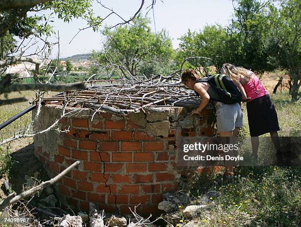 British tourists look down a well while searching for the missing three-year-old girl Madeleine McCann in wasteland on May 8, 2007 outside the...
