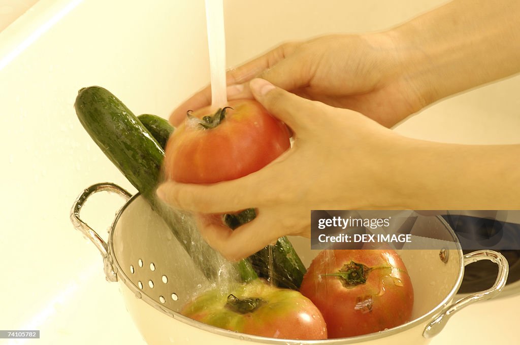 Close-up of a person's hands washing vegetables