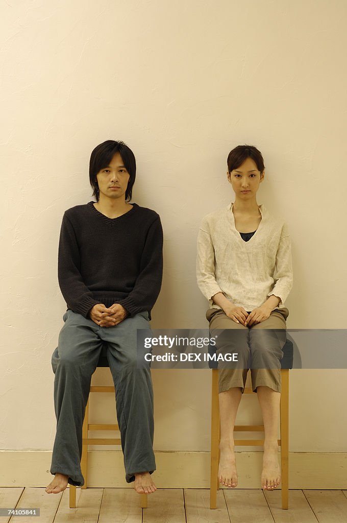 Portrait of a young couple sitting on stools
