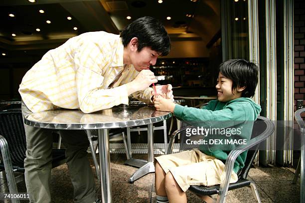 close-up of a young man and his son in restaurant - bendy straw stock pictures, royalty-free photos & images