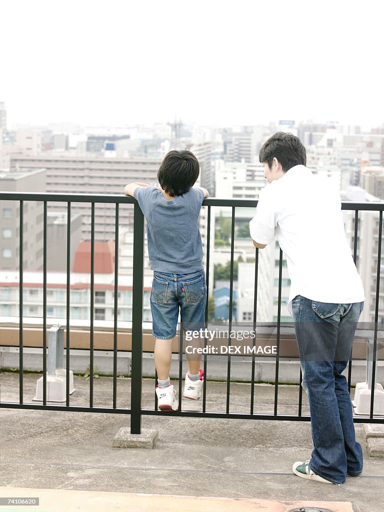 Rear view of two people holding a railing