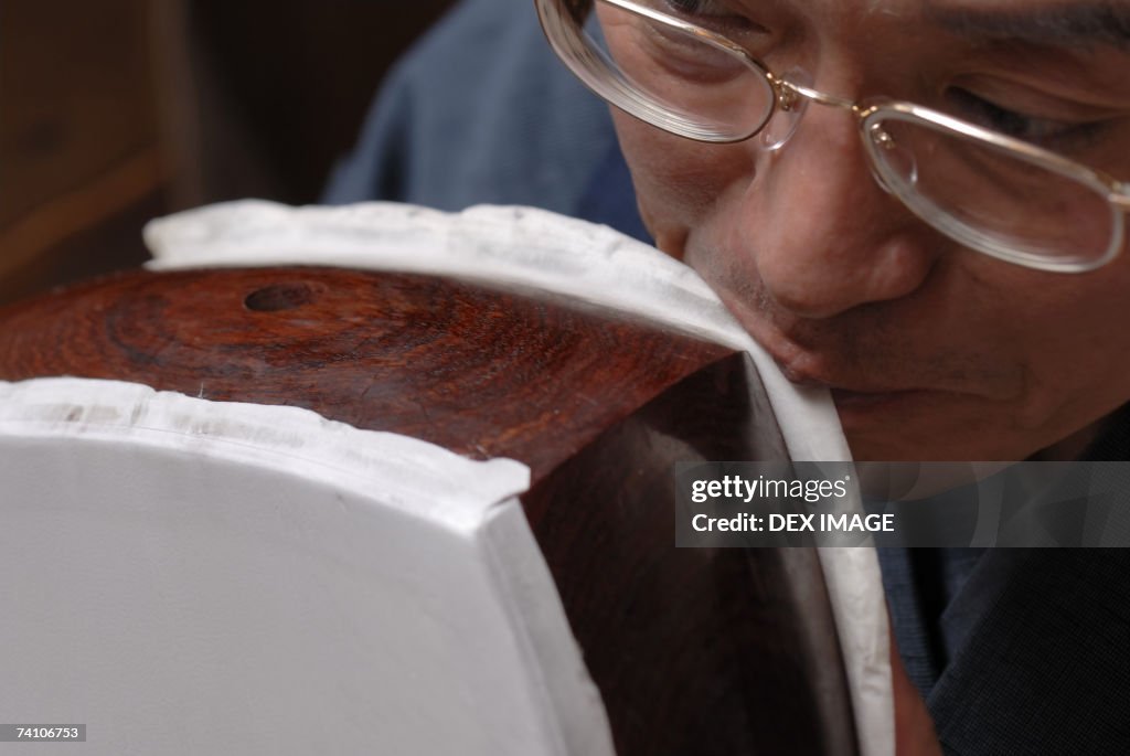 Close-up of a carpenter removing animal hide with his teeth