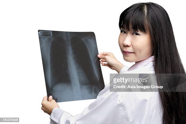 doctor holding x-ray, looking over shoulder - doctor looking over shoulder stock pictures, royalty-free photos & images