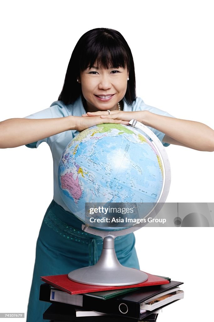 Woman leaning on globe, smiling