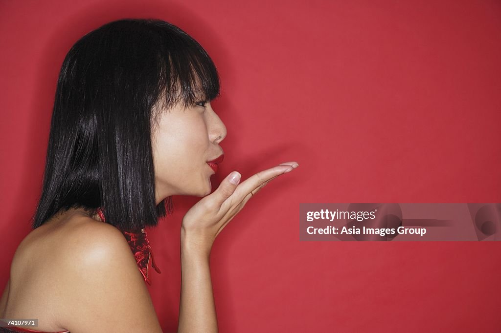 Woman with bob haircut, blowing a kiss, side view