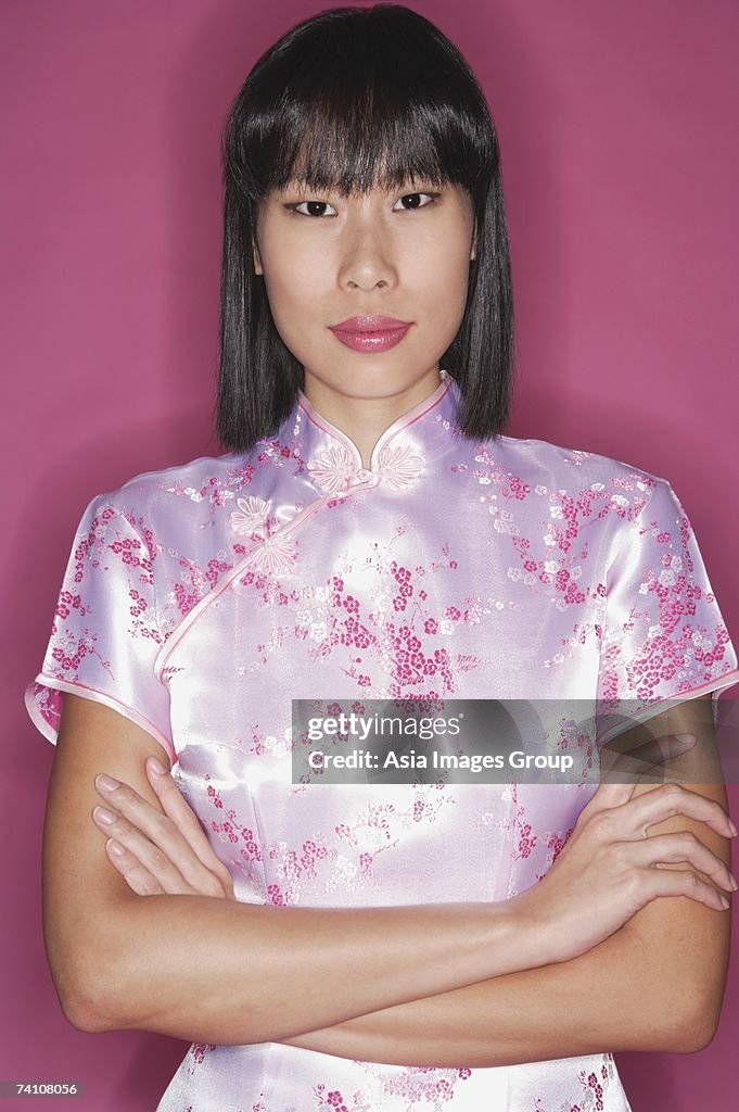 Woman in pink cheongsam, arms crossed