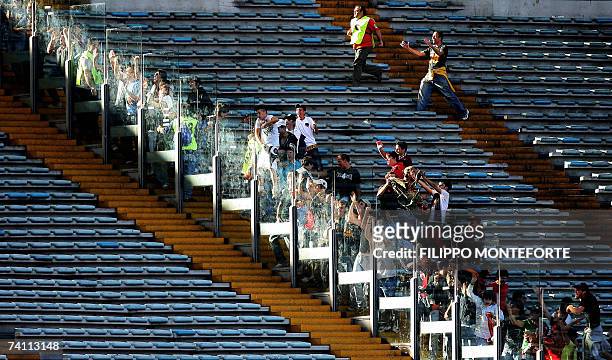 Roma's football club fans run to the glass that separates them from Inter Milan's supporters after their team scored during the Coppa Italia first...