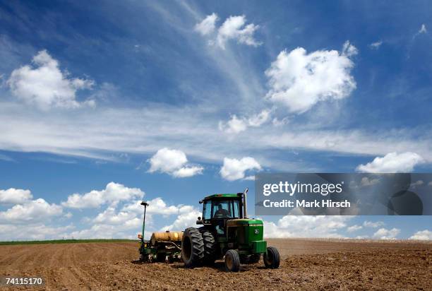 Iowa farmer Ernie "George" Goebel pulls a corn planter behind his John Deere tractor while planting corn in a field on the farm he was raised on May...